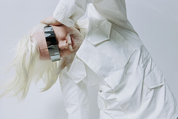Fashion model with long white hair in futuristic sunglasses against a soft white background,...