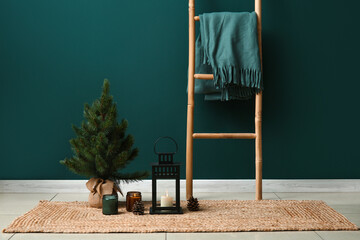 Lantern with burning candles, Christmas tree and ladder near color wall