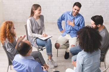 Cheerful man appreciates support of people at rehab group meeting, empty space