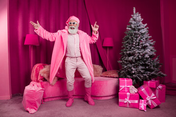 Photo of funky senior bearded male santa claus dance cool boots fur coat fluffy nighty hat sunglasses pink new year celebration decor x-mas