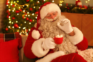 Santa Claus drinking hot chocolate with marshmallows at home on Christmas eve