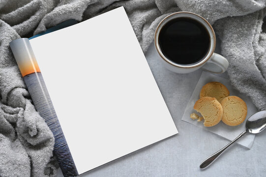 An open magazine laying on a table or desk with a white blank page for mock up.