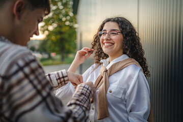 Boyfriend ties the girlfriend's sweater in front black wall
