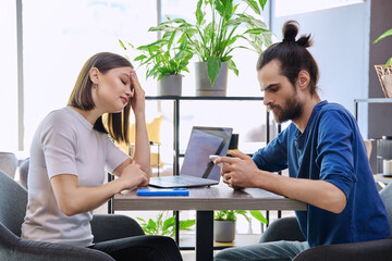 Serious sad upset young couple sitting together in cafeteria