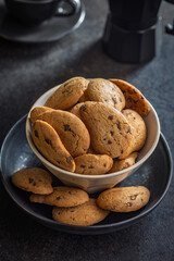 Biscotti frollini con gocce di cioccolato. Chocolate cookies on plate on black table.