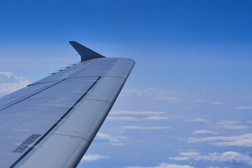 Airplane wing soaring above white clouds