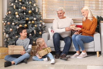 Obraz premium Little children with Christmas presents and their grandparents at home