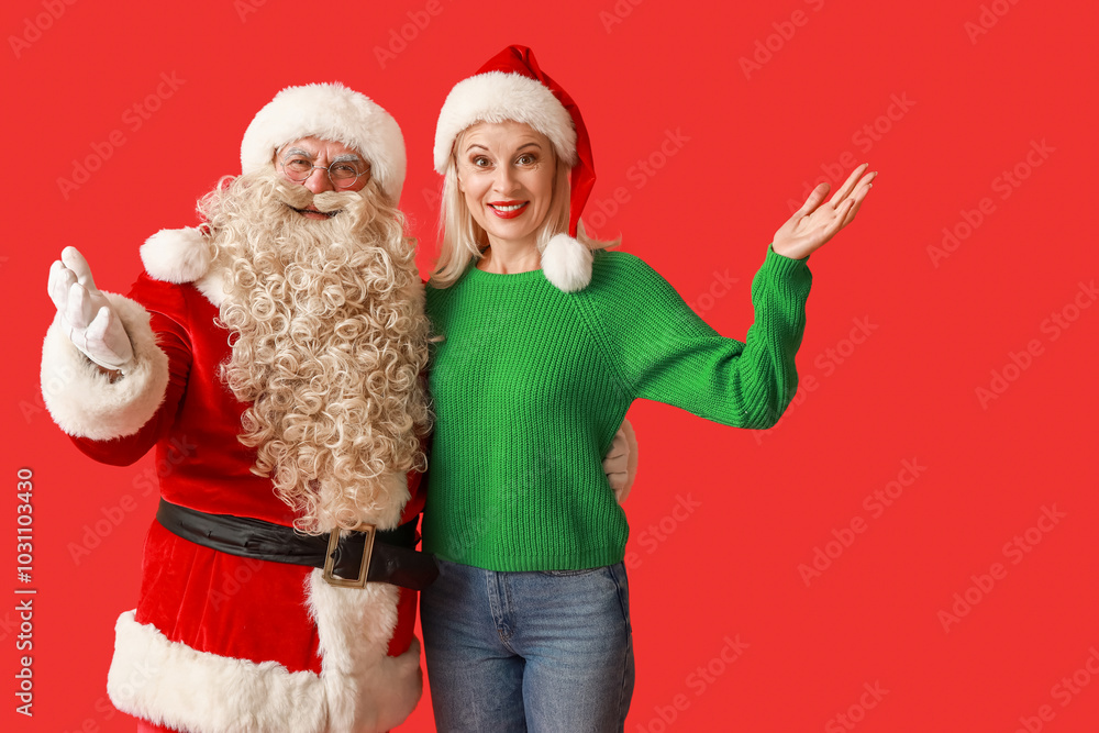 Poster Santa Claus and beautiful mature woman in Christmas hats on red background