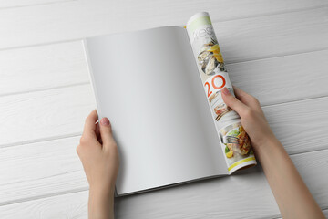 Woman reading magazine at white wooden table, top view. Mockup for design
