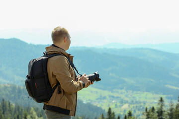 Fototapeta premium Photographer with backpack and camera taking picture of beautiful mountains. Space for text