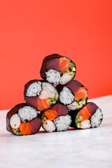 Japanese set of sushi rolls with raw tuna, salmon, shrimp, cucumber and rice on red background.
