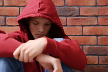 Loneliness concept. Sad teenage boy near brick wall © New Africa