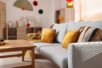 Interior of festive living room with grey sofa and traditional Chinese decorations. Chinese New Year celebration