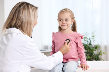 Fototapeta premium Doctor examining little girl with stethoscope in hospital