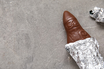 Chocolate Santa Claus candy wrapped in aluminium foil on grunge background, closeup