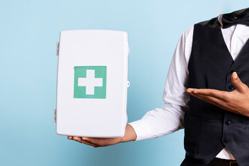 Hotel concierge doorman pointing at a first aid kit used for medical purposes, advertising...