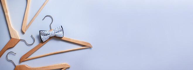Wooden hanger with checkered bow tie surrounded by other clothes hangers. Sale banner. Selective focus, place for text