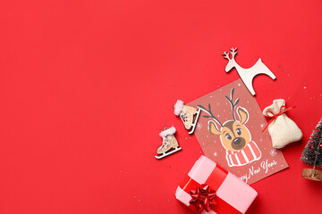 Beautiful composition with gift box, greeting card and different Christmas decorations on red background