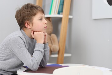 Autism concept. Lonely little boy at table indoors, space for text