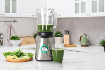 Modern blender with smoothie and ingredients on white marble table in kitchen