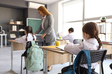 Obraz premium Little schoolgirl having lesson in classroom, back view