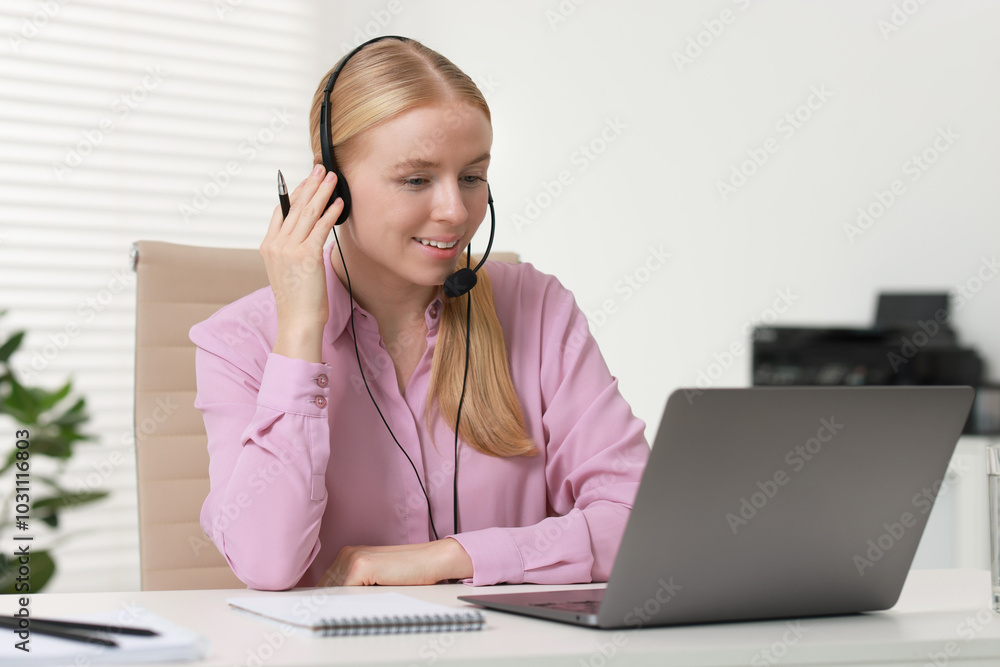 Poster interpreter in headset working with laptop at table indoors