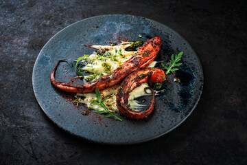 Authentical Italian polpo alla griglia su crema di patate with barbecued octopus, potato creme and fried bacon served as close-up on a Nordic design plate