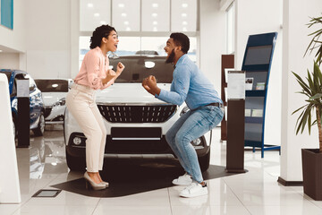 New Car Concept. Joyful Afro Family Couple Celebrating Buying Auto Shaking Fists And Shouting...