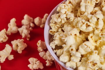 Striped cylindrical container with popcorn ready to enter the cinema, on a red background