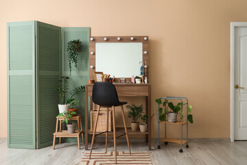 Interior of makeup room with table, plants and folding screen