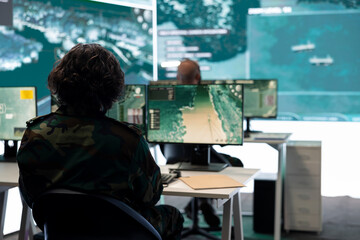 IT operator monitoring surveillance radar footage from CCTV system, using a big screen in military...