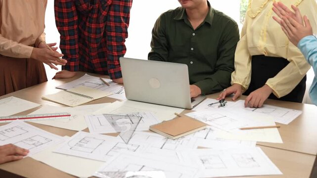 Architect and safety engineer celebrate success design building blueprint project on laptop on table with architectural document and wooden block scatter around at modern office. Closeup. Delineation.