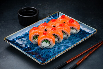 Sushi rolls Philadelphia with salmon, cream cheese, cucumber, rice, nori and soy sauce.