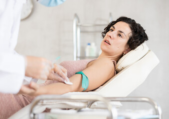 Male anesthesiologist injecting anesthetic into vein on her arm with syringe in a cosmetology clinic