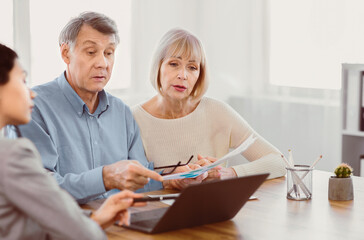 Mortgage Calculator. Focused senior couple comparing current refinance interest rates with...