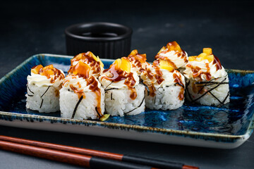 Set of sushi rolls with tuna, cream cheese, avocado, mango and teriyaki sauce.