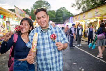 Portrait of friends enjoying the traditional snacks they bought at the fair.