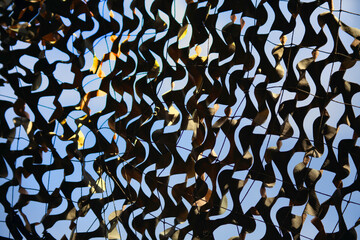 Olive military mesh with torn holes with shadows from bright sunlight. Camouflage net and the blue sky