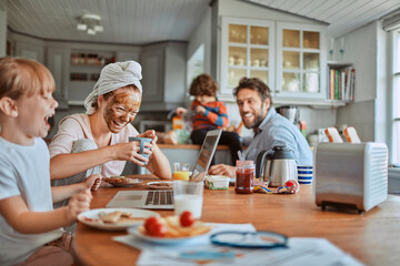 Family laughing during breakfast in kitchen