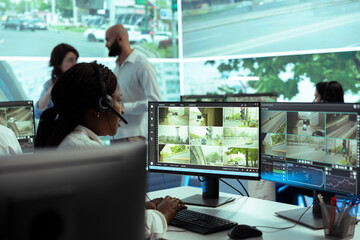 African american dispatch operator uses satellite sensors system to ensure public safety on city...