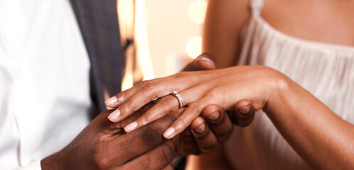 Afro guy putting diamond ring on his girlfriend finger, close up