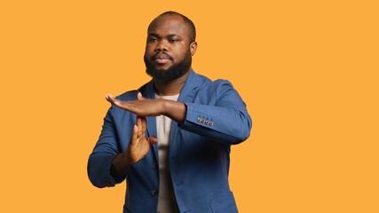 Portrait of assertive BIPOC man asking for timeout, doing hand gestures, feeling fatigued. Unhappy...