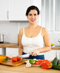 Smiling housewife cooking salad in the kitchen at home