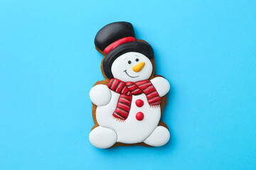 Tasty Christmas cookie in shape of snowman on light blue background, top view