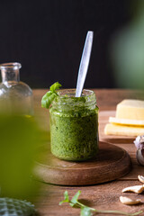 Basil pesto in a jar on a rustic table. Vertical photo