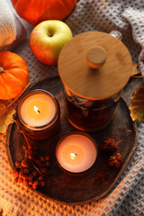 Burning candles, freshly brewed tea and autumn decor on fabric, above view
