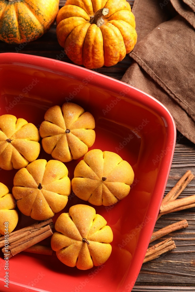 Poster Baking tray with tasty pumpkin shaped buns and cinnamon sticks on wooden table, flat lay