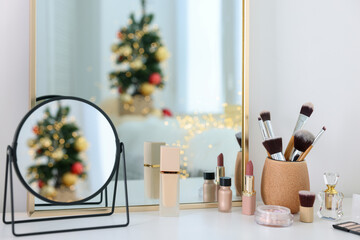 Makeup brushes, cosmetics, mirror and perfume on white table indoors