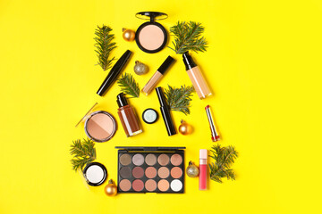 Flat lay composition with makeup products and Christmas decor on yellow background