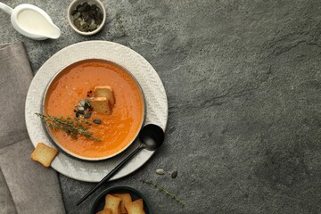 Delicious pumpkin soup with spices served on grey textured table, flat lay. Space for text